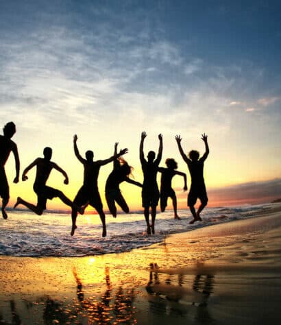 Family jumping for joy at the beach during sunset