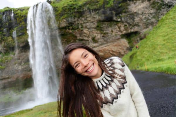 Woman smiling in front of waterfall in Iceland