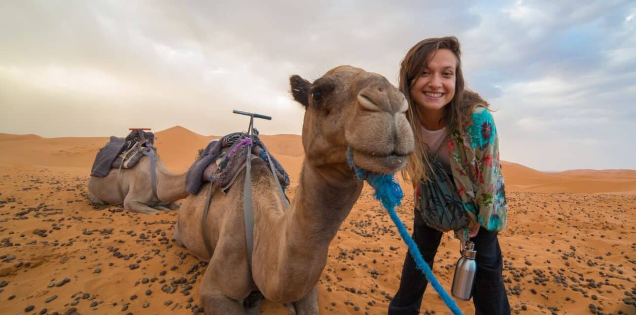 Young girl smiling with camel in the desert of Morocco