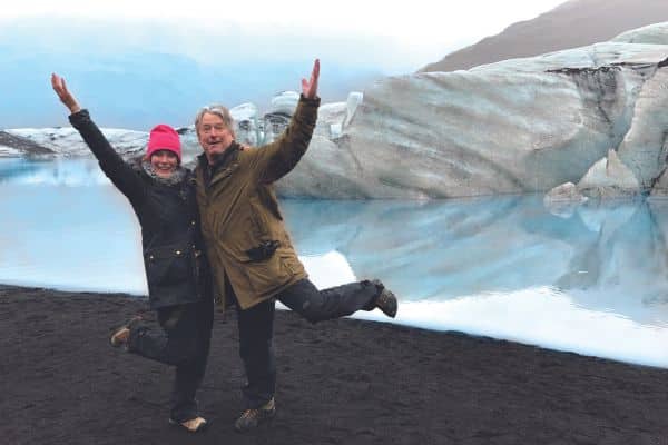 Travelers standing on a cliff near a glacier in Iceland