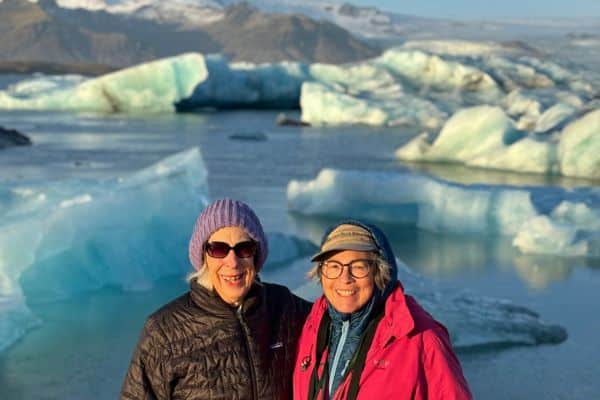 Women in Iceland smiling in front of the beautiful icy landscapes on tour.