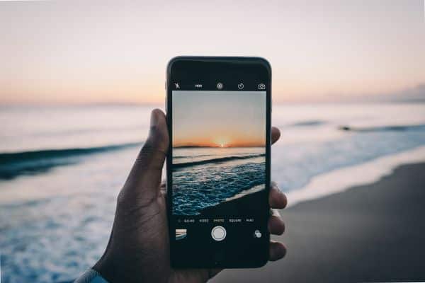 An iphone camera taking a picture of a beach at sunset. 